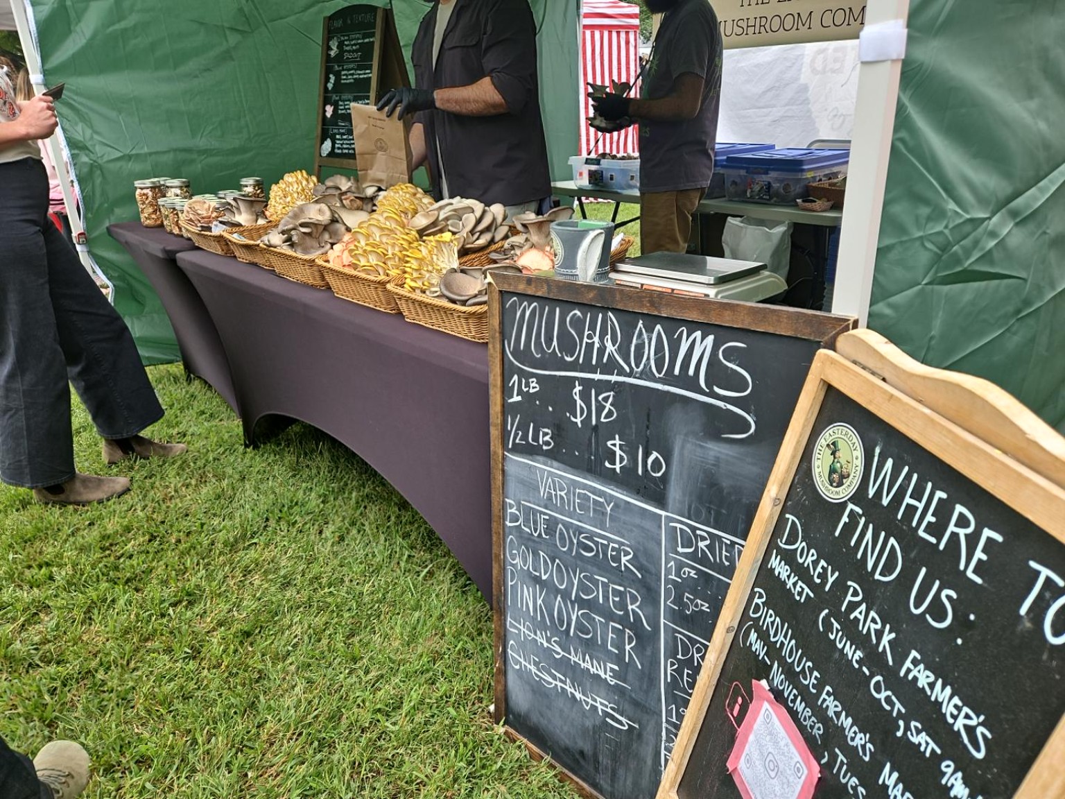 A mushroom vendor booth with baskets and pricing signs.